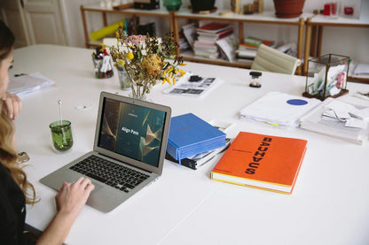 Person using a laptop displaying 'Align Pass' Swift course on a desk with books, a notebook, and flowers in the background.