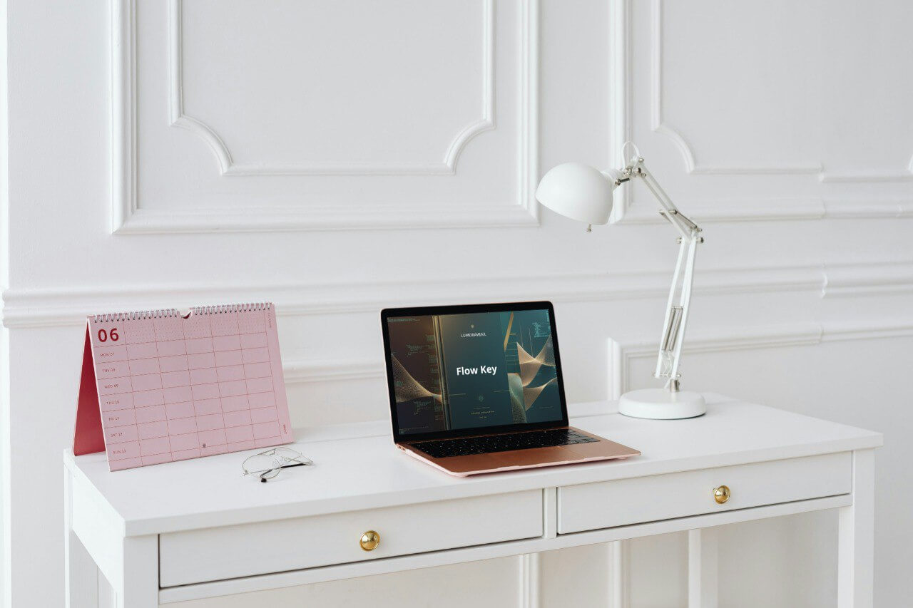 White desk with laptop displaying 'Flow Key' Swift PDF course, lamp, and calendar against a white paneled wall