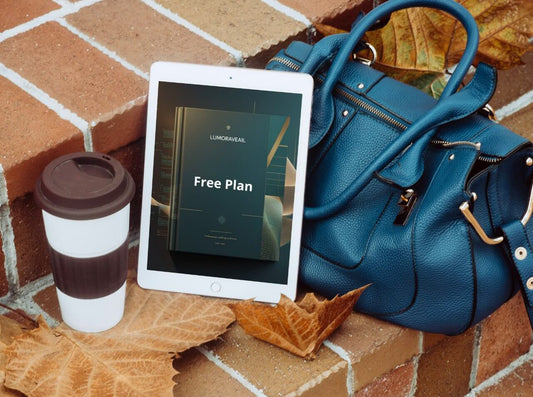 Blue handbag, tablet displaying a 'Free Plan' Swift PDF course, and coffee cup on a brick surface with autumn leaves.